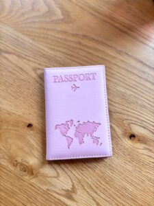 Pink passport cover, just says passport with a map of the world in a darker shade of pink on it. 